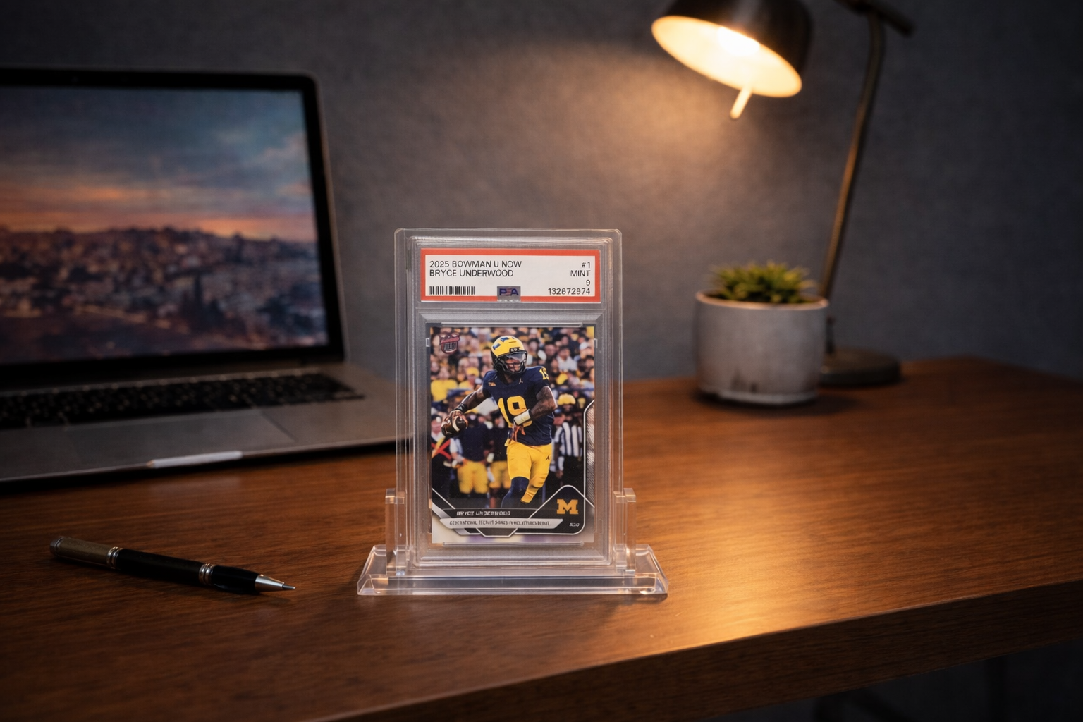 Trading card in a protective case on a desk with a laptop and lamp in the background