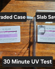 Two wall-mounted UV protective cases labeled 'Graded Case' and 'Slab Saver' for comic books, with a 30 Minute UV Test card placed inside each case, displayed on a wooden surface.
